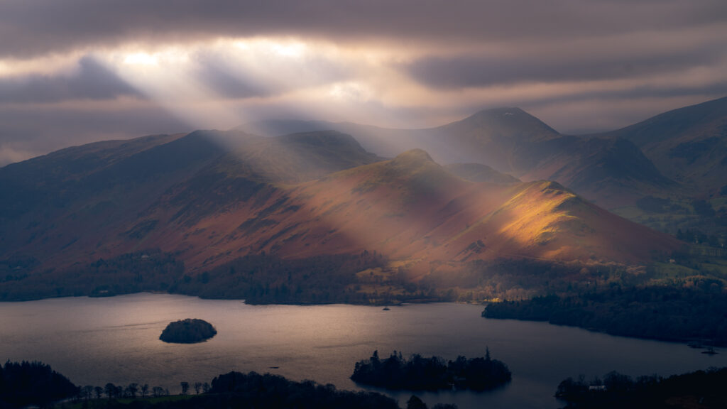 Cloudy Day Photography - Rays of sunlight penetrate the cloud, at Derwent Water, Lake District, UK. Photo by Chris Bennett.
